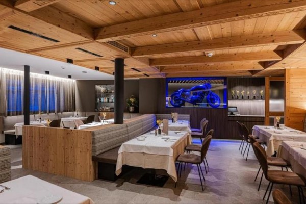 Nowoczesna restauracja z drewnianym wnętrzem i wystawionym niebieskim motocyklem.