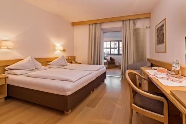 Nowoczesny pokój hotelowy z podwójnym łóżkiem, biurkiem i sofą.