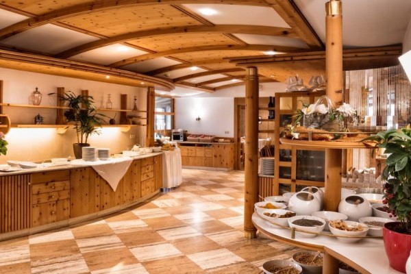 Wnętrze hotelowej restauracji z drewnianymi meblami i bufetem śniadaniowym.