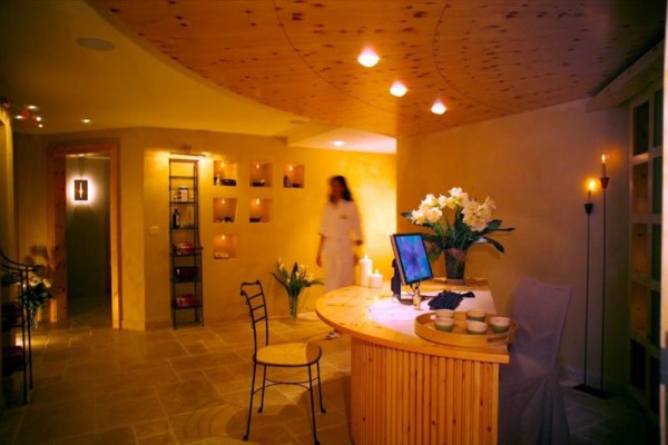 Wnętrze relaksacyjnego spa ze świecami i kwiatami na drewnianym recepcyjnym blacie.