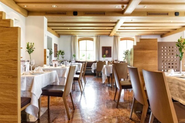 Wnętrze restauracji z nakrytymi stołami i drewnianym sufitem.