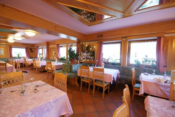 Restauracja z drewnianym wnętrzem, nakrytymi stołami i różowymi obrusami.