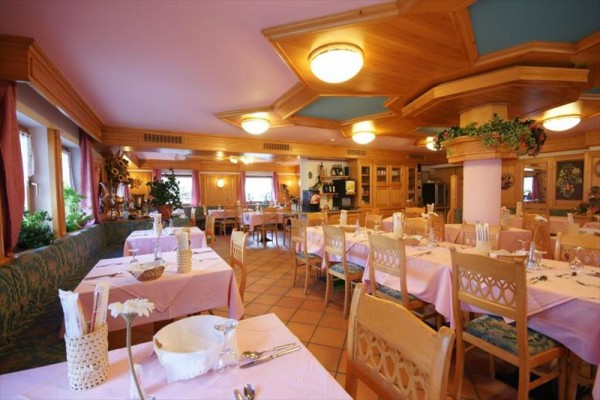 Przestronna restauracja z drewnianymi meblami i różowymi obrusami.