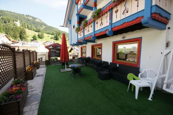 Zewnętrzny taras hotelowy z kolorowymi dekoracjami i widokiem na wzgórza.