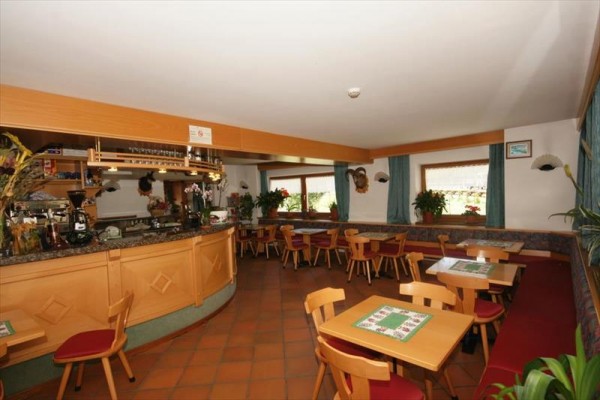 Restauracja z drewnianymi meblami, barem i kwiatami na oknach.
