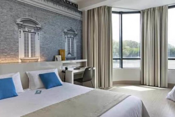 Nowoczesny pokój hotelowy z dużymi oknami i dwoma łóżkami.