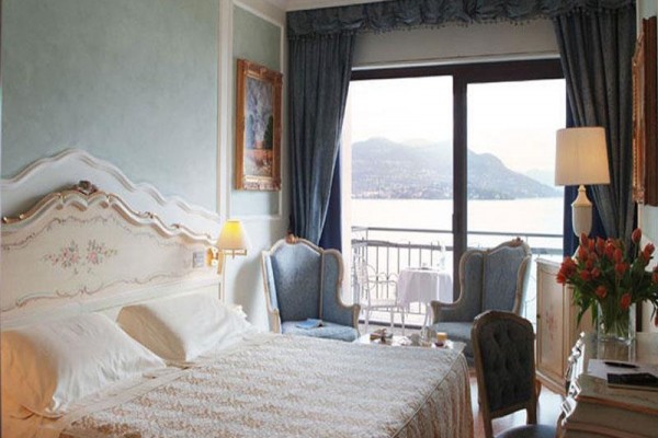 Luksusowy pokój hotelowy z widokiem na jezioro i góry, wyposażony w eleganckie meble.