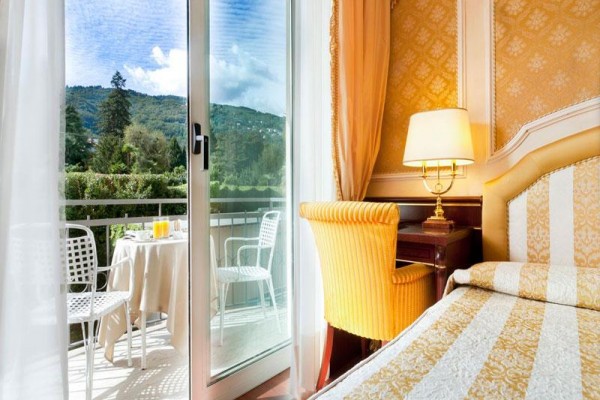Elegancki pokój hotelowy z widokiem na balkon i góry w tle.