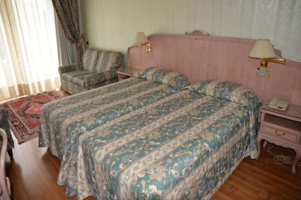 Dwa łóżka pojedyncze z kwiecistą pościelą w pokoju hotelowym z sofą i balkonem.