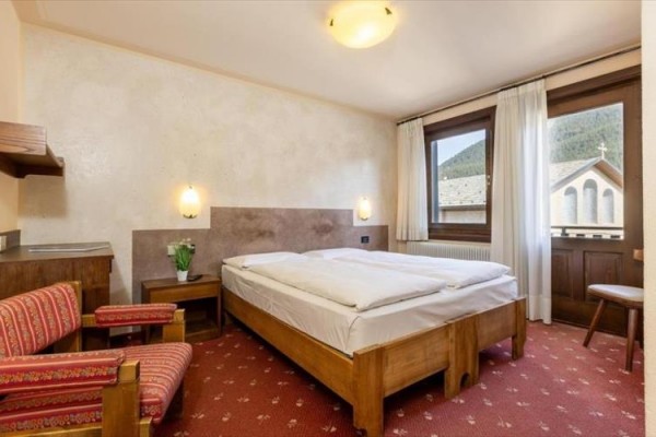 Pokój hotelowy z podwójnym łóżkiem, dwoma fotelami i widokiem na kościół.