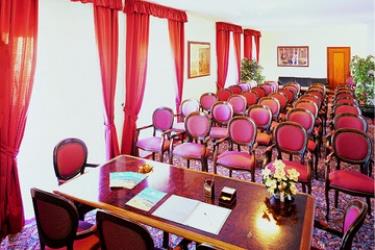 Sala konferencyjna z rzędami krzeseł i stolikiem z kwiatami.
