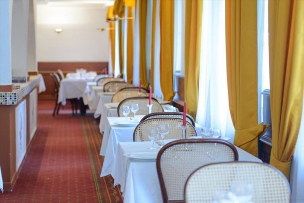 Elegancka restauracja z nakrytymi stołami i żółtymi zasłonami.