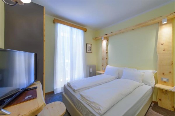 Jasny pokój hotelowy z podwójnym łóżkiem i naturalnym oświetleniem.