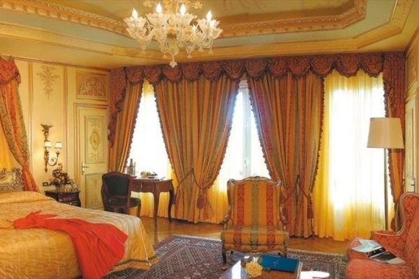 Luksusowy pokój z bogatymi zasłonami, żyrandolami i eleganckimi meblami.