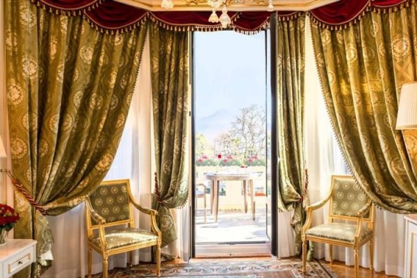 Eleganckie wnętrze z ozdobnymi zasłonami, dwoma krzesłami i widokiem na balkon.