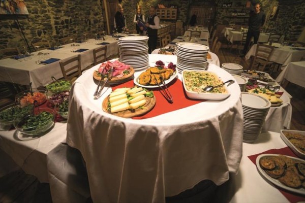 Okrągły stół pełen różnych przystawek i talerzy w rustykalnej restauracji.