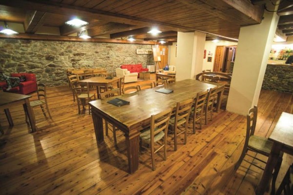 Drewniane wnętrze restauracji z kamiennymi ścianami i krzesłami rozmieszczonymi wokół stołów.
