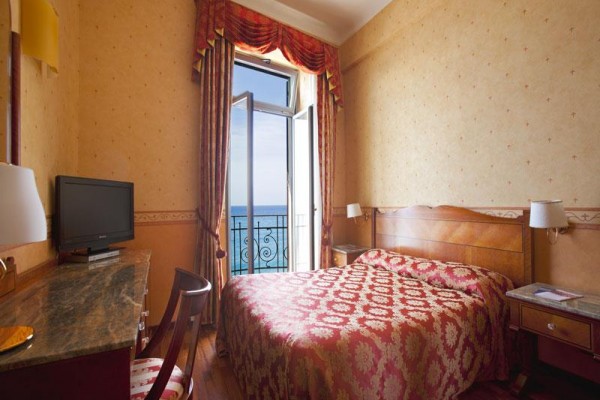 Pokój hotelowy z otwartym balkonem i widokiem na morze.