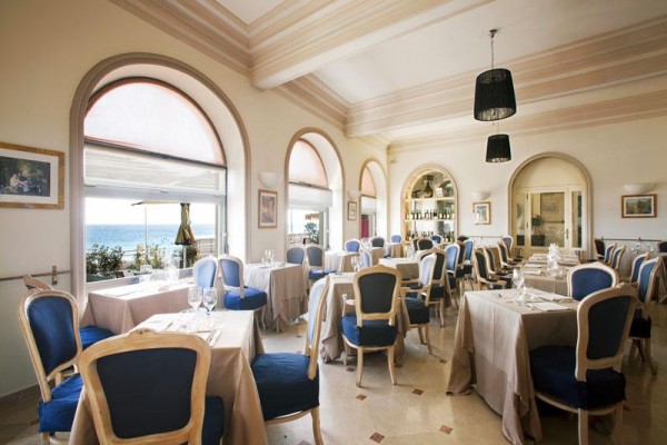 Elegancka restauracja z niebieskimi krzesłami i widokiem na morze.