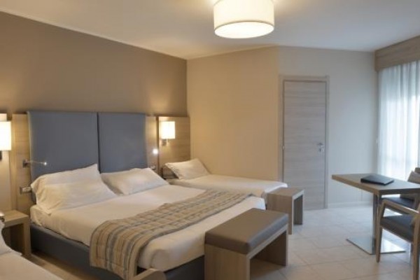 Elegancki pokój hotelowy z łóżkiem małżeńskim, pojedynczym łóżkiem i biurkiem.