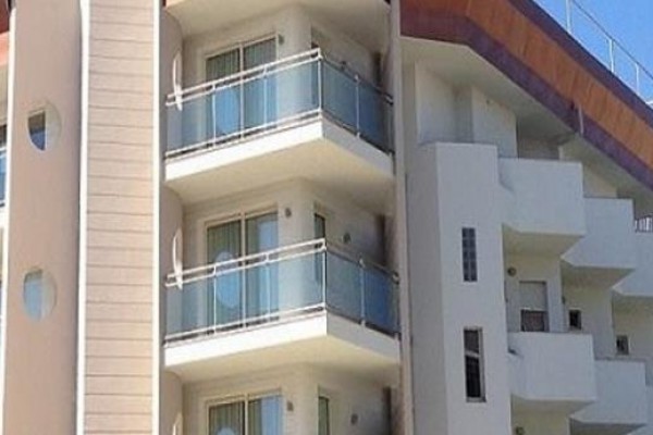 Nowoczesny budynek z balkonami i niebieskimi szklanymi balustradami.