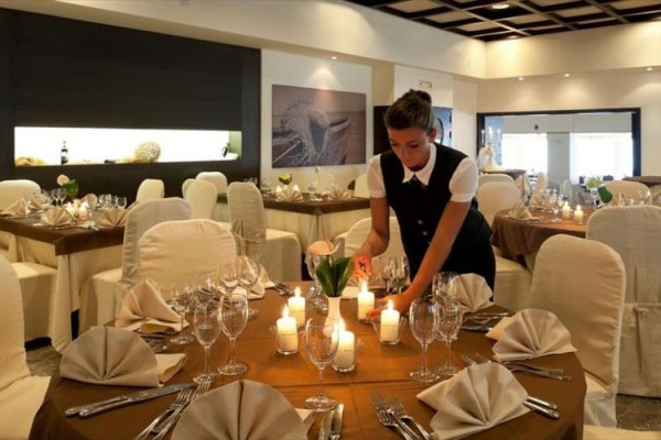 Kelnerka przygotowuje stół z zapalonymi świecami w eleganckiej restauracji.