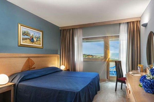 Nowoczesny pokój hotelowy z podwójnym łóżkiem i oknem z widokiem na morze.