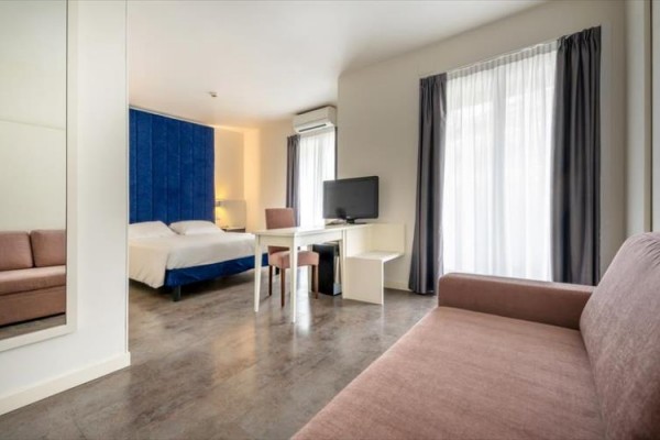 Nowoczesny pokój hotelowy z podwójnym łóżkiem, telewizorem i kanapą.