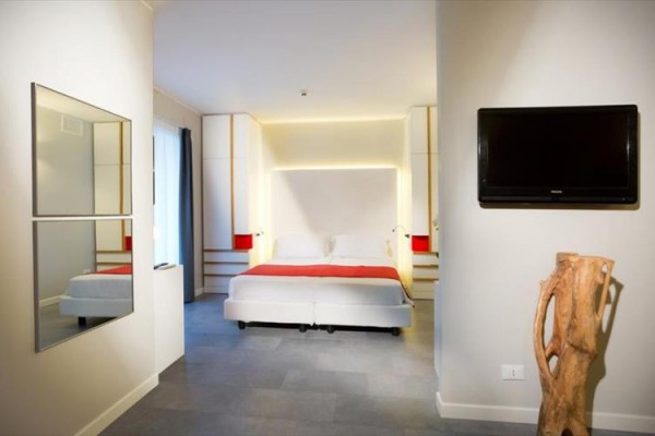 Nowoczesny pokój hotelowy z podwójnym łóżkiem, telewizorem na ścianie i drewnianą dekoracją.