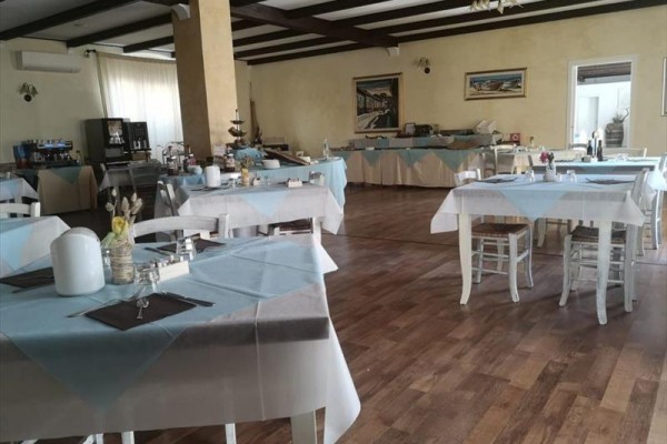 Restauracja z drewnianą podłogą i stołami nakrytymi niebiesko-białymi obrusami.