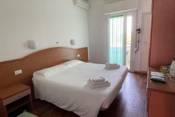 Pokój hotelowy z łóżkiem małżeńskim i balkonem.