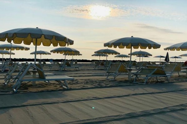 Plaża z leżakami i parasolami o zachodzie słońca.