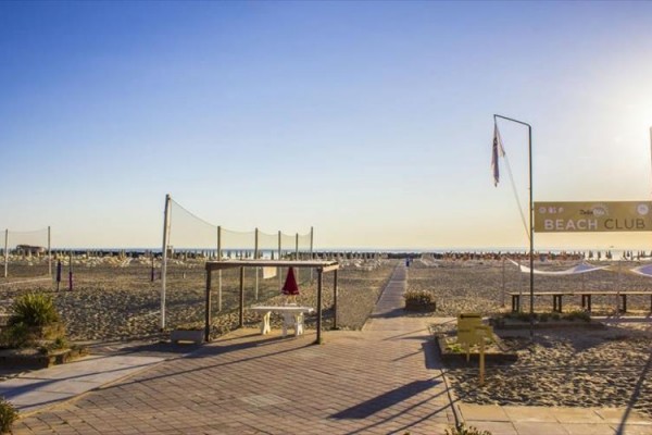 Plaża z leżakami i parasolami o zachodzie słońca, z napisem 