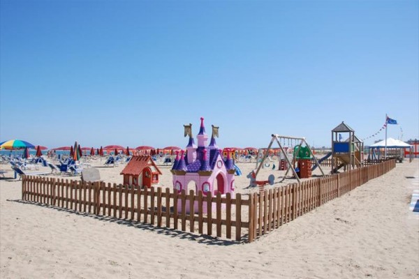 Plac zabaw na plaży z piaskiem i kolorowym zamkiem.