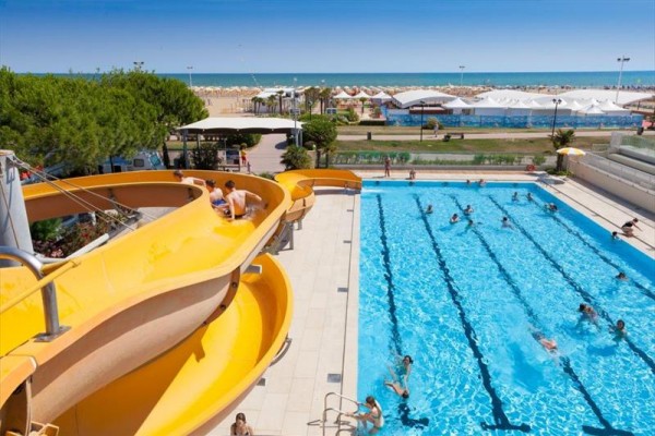 Basen pływacki z wodną zjeżdżalnią i widokiem na plażę.