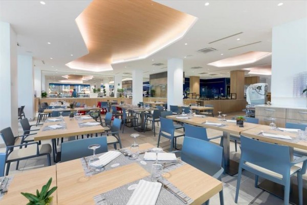 Nowoczesna restauracja z drewnianymi stołami i niebieskimi krzesłami, gotowa do obsługi.