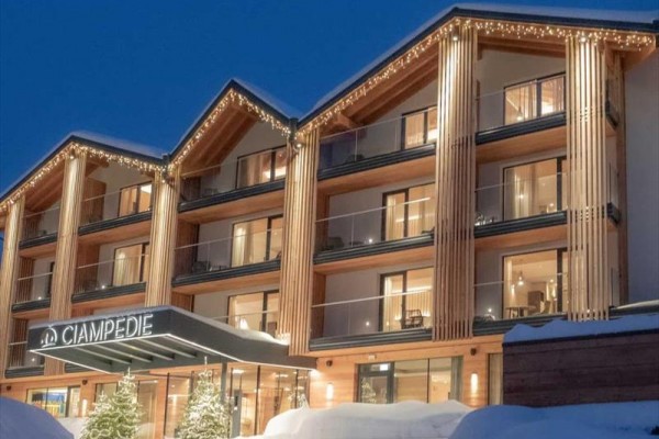 Nowoczesny drewniany hotel górski zimą z oświetleniem i śniegiem na dachu.
