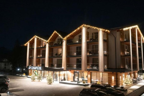 Nowoczesny hotel górski nocą oświetlony świątecznymi lampkami.