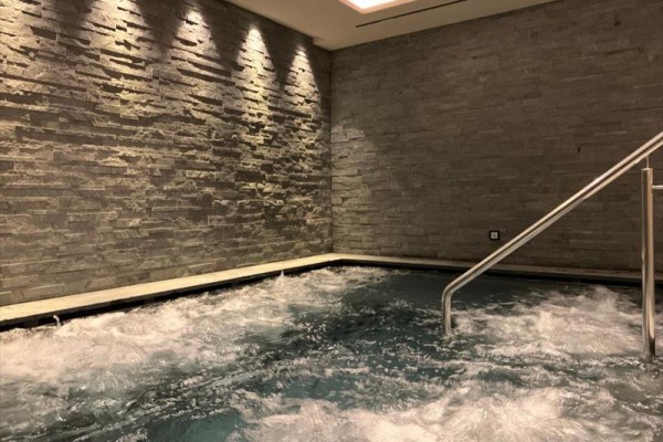 Wewnętrzne jacuzzi z kamiennymi ścianami i górnym oświetleniem.