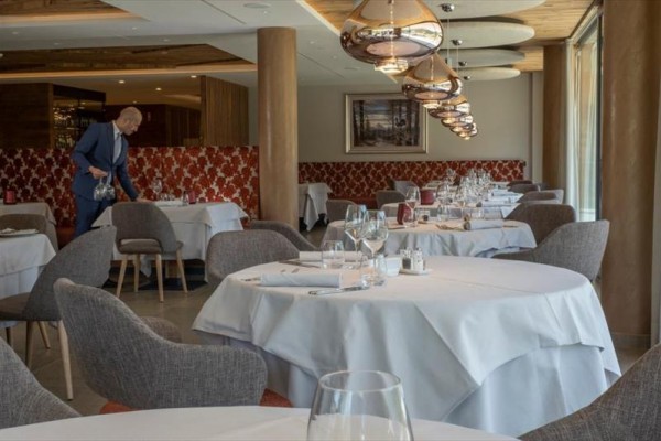 Elegancka restauracja z okrągłymi stołami i kelnerem przygotowującym stół.