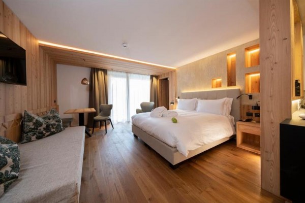 Nowoczesny pokój hotelowy z podwójnym łóżkiem, drewnianym wnętrzem i dużym oknem na balkon.