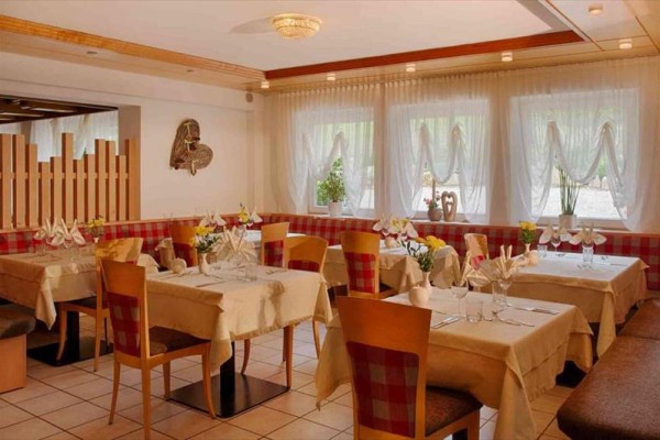 Przytulna restauracja z nakrytymi stołami i krzesłami w czerwono-białą kratę.