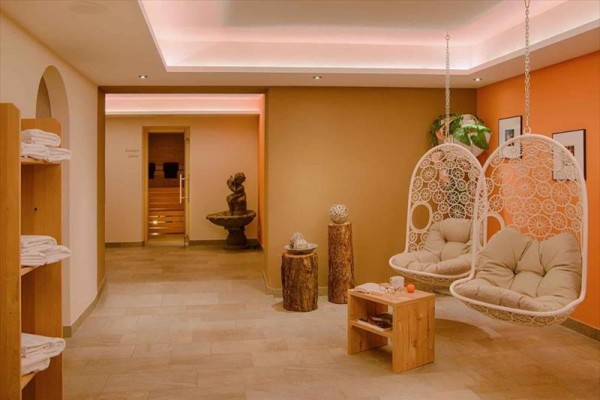 Wnętrze spa z dwoma wiszącymi fotelami i drzwiami do sauny.
