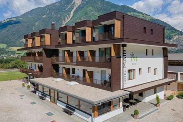 Nowoczesny hotel z drewnianymi balkonami na tle górskiego krajobrazu.