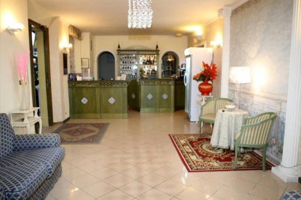 Elegancka recepcja hotelowa z drewnianym blatem, fotelami, stolikami i dekoracyjnymi dywanami.