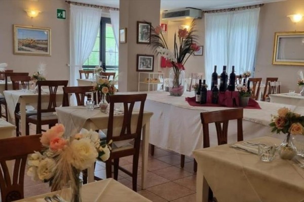 Restauracja z drewnianymi krzesłami i stołami ozdobionymi aranżacjami kwiatowymi.