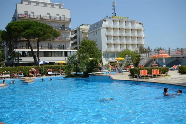 Basen na zewnątrz z ludźmi, w tle wielopiętrowy hotel.