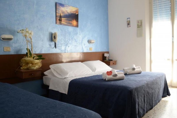 Pokój hotelowy z niebieską ścianą, łóżkiem i balkonem.