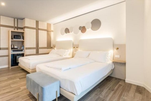 Nowoczesny pokój hotelowy z dwoma łóżkami małżeńskimi i dekoracją na ścianie.