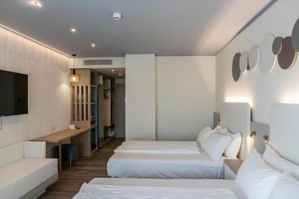 Nowoczesny pokój hotelowy z dwoma pojedynczymi łóżkami, telewizorem i biurkiem.